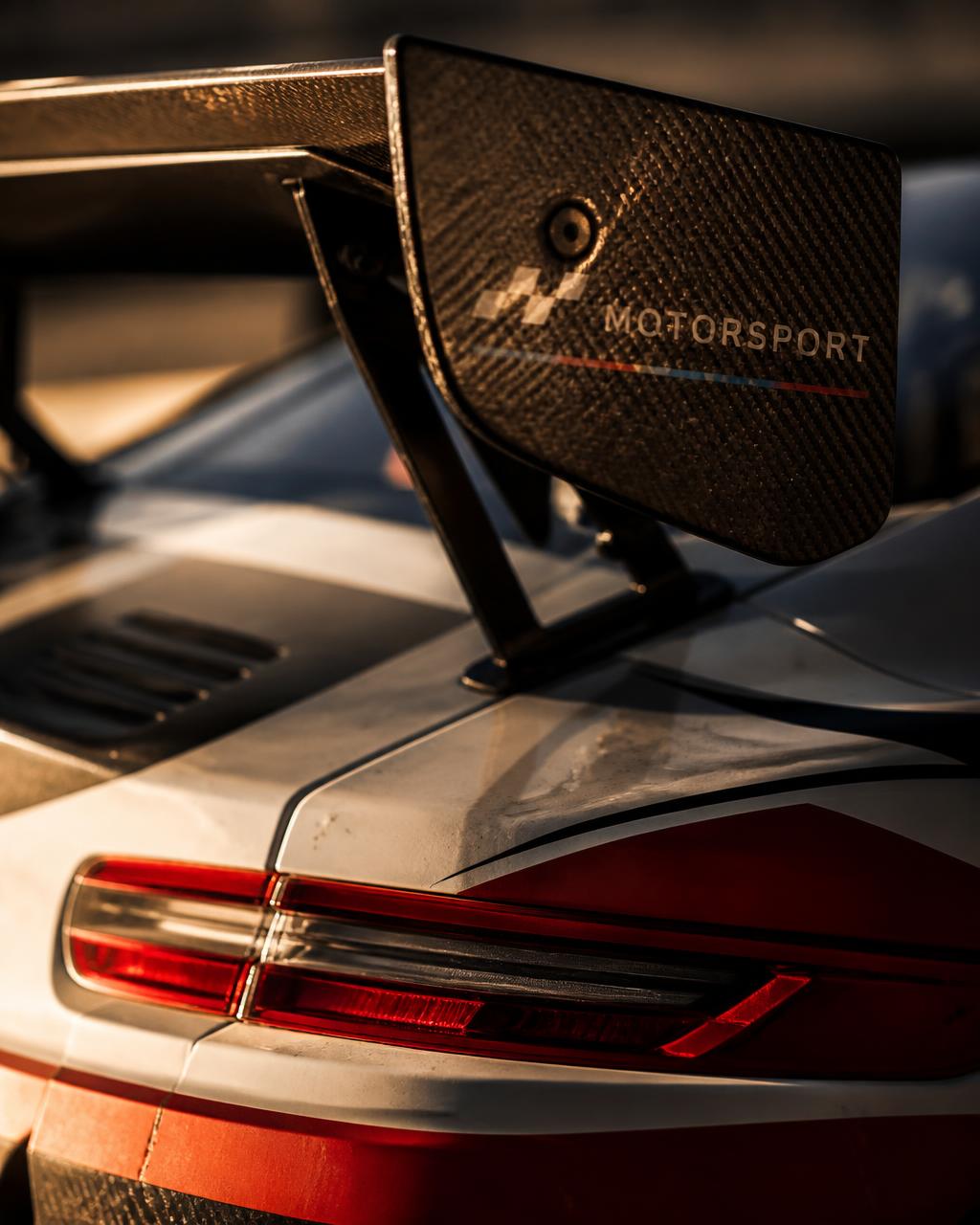 Detail crop of a carbon fibre rear wing and tail light in golden hour light